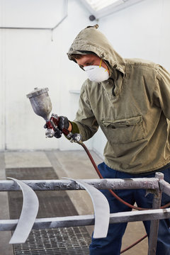 Man in protective clothes and respirator paints car details
