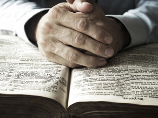 hands praying on bible