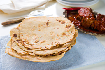 Chapatti roti and Indian food on dining table.