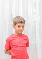 Blonde boy in a red shirt indoors