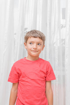 Blonde boy in a red shirt indoors