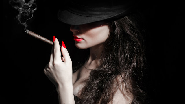 young woman with black hat, cigarillo and red nails