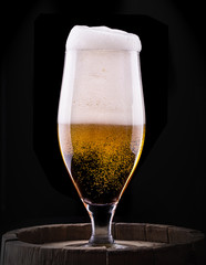 Frosty glass of light beer on black background
