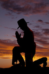 Naklejka premium Silhouete cowboy kneel head down.