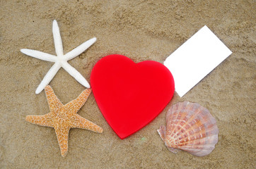 Heart shape, starfishes, seashell and paper on the beach