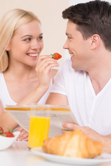 Obraz na płótnie Canvas Feeding him with berry. Young loving couple looking at each othe