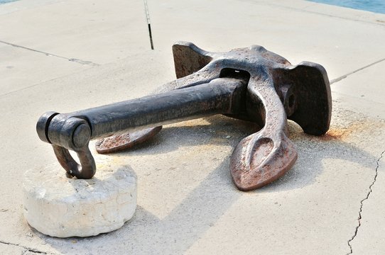 Old rusty ship anchor on port. Podgora, Croatia