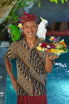 Asian waiter with a tray of tropical fruits in an exotic setting
