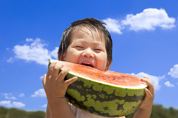 青空の下でスイカを食べる子供