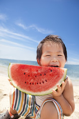夏の海でスイカを食べる子供