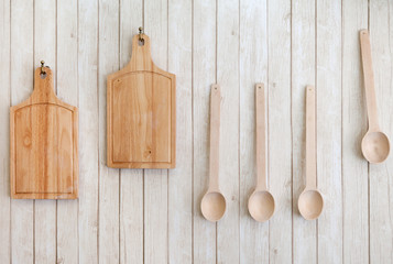 cutting boards and wooden spoons hanging on the wall