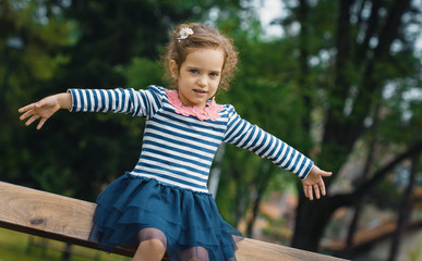Playful little girl in park with open arms - outstretched