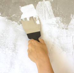 Woman's hand with a spatula wall plasters in room during repair