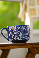 blue teacup on a table outdoors with a blanket in the background