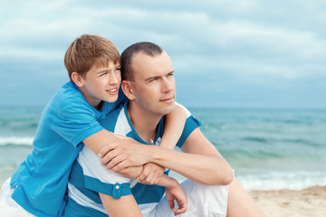 Father and son sitting on sea