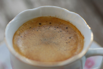 close up on espresso in a white porcelain cup with gold lining