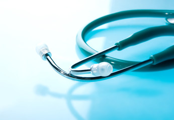 Stethoscope on blue, reflective background