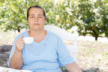 Senior woman drinking coffee in the garden