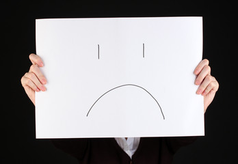 Woman holding paper with sad emoticon, isolated on black