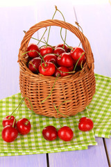 Cherry berries in wicker basket on wooden table close up