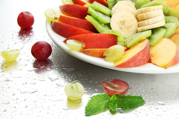 Assortment of sliced fruits on plate with drops