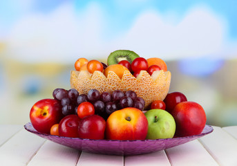 Assortment of juicy fruits on wooden table, on bright