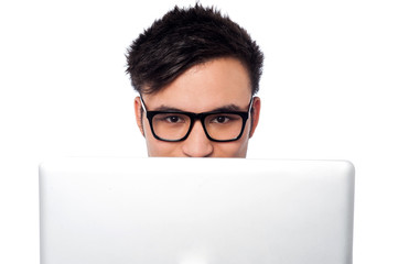 Boy trying to hide his face behind laptop
