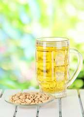 Beer in glass and nuts on table on nature background