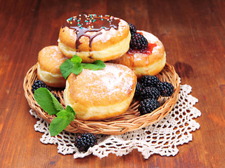 Tasty donuts with chocolate and berries on wooden table