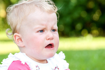 Crying baby sitting alone in the meadow