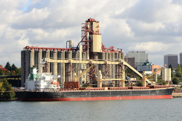 Obraz premium Large grain ship next to a silo loading facility