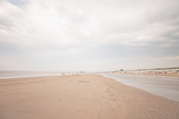Long exposure shot of beach with blue cloudy sky.