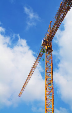 Yellow tower crane on a beautiful blue sky background