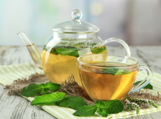 Teapot and cup of herbal tea with fresh mint flowers