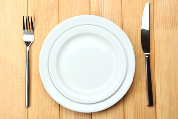 Knife, color plate and fork, on wooden background