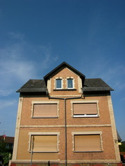 Wohnhaus mit Dachgaube, Spitzgiebel und Backsteinfassade in Beige und Naturfarben im Sommer vor...