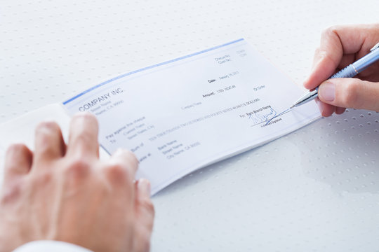 Close-up Of Hand Filling Cheque