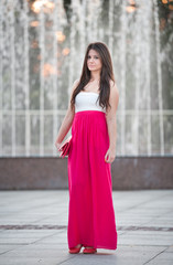 Fototapeta premium young woman with long red skirt in front of a fountain