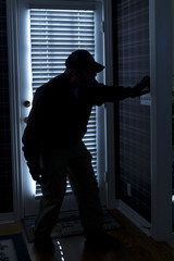 Burglar Breaking In To Home At Night Through Back Door