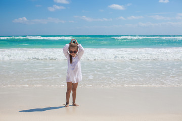 Adorable toddler girl in white dress walking at exotic beach