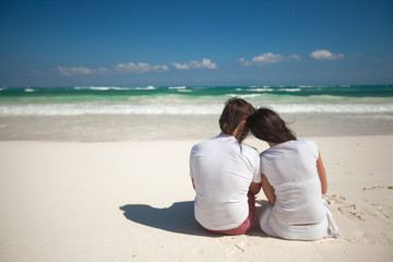 Fototapeta na wymiar Back view of young couple at tropical white beach