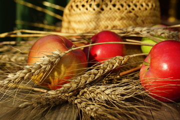 rural composition with apples, wheat and straw hat