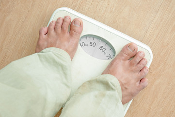 Man standing on weight scales with bare foot