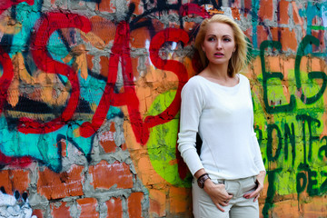 Portrait of fashion girl standing near wall with graffiti