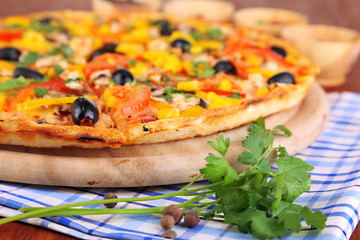 Tasty pizza with kitchen herbs on wooden table close-up