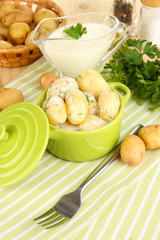 Tender young potatoes with sour cream and herbs in pan