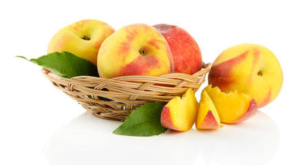Ripe sweet peaches with leaves in basket, isolated on white