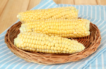 Fresh corn on wicker mat, on wooden background