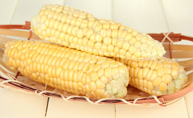 Fresh corn on wicker mat, on wooden background