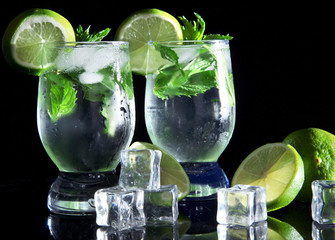 Glasses of cocktail with ice on black background